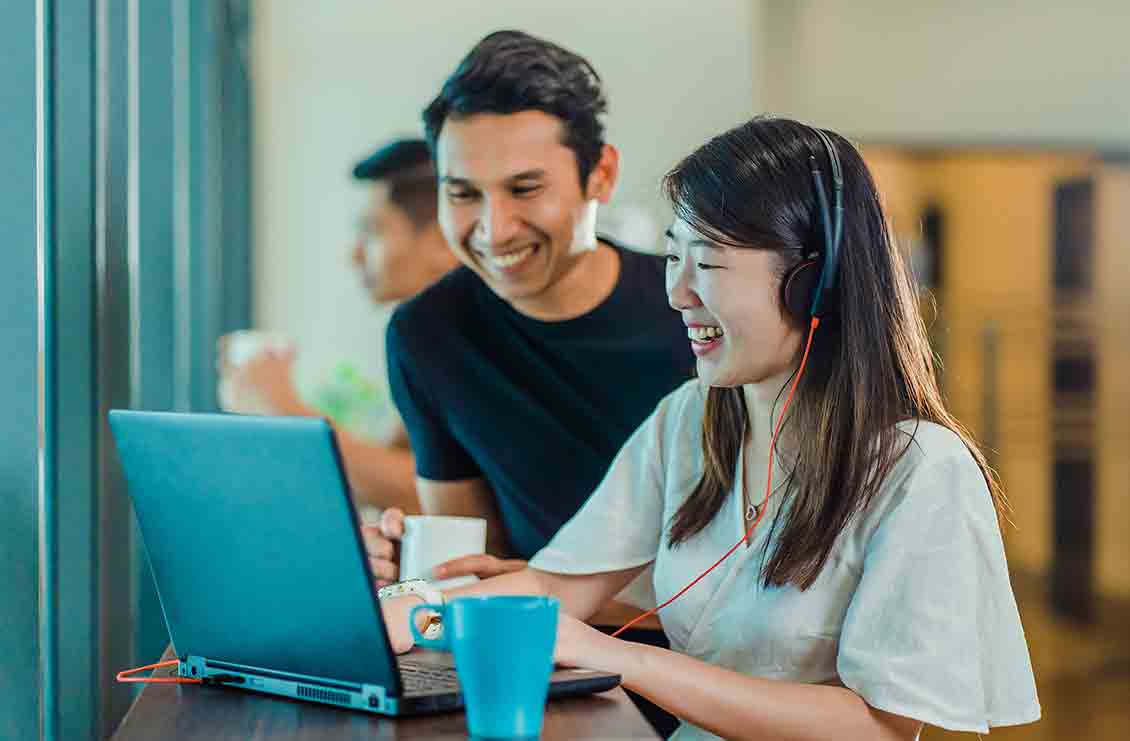 Asian man and woman intern working together on a laptop computer.