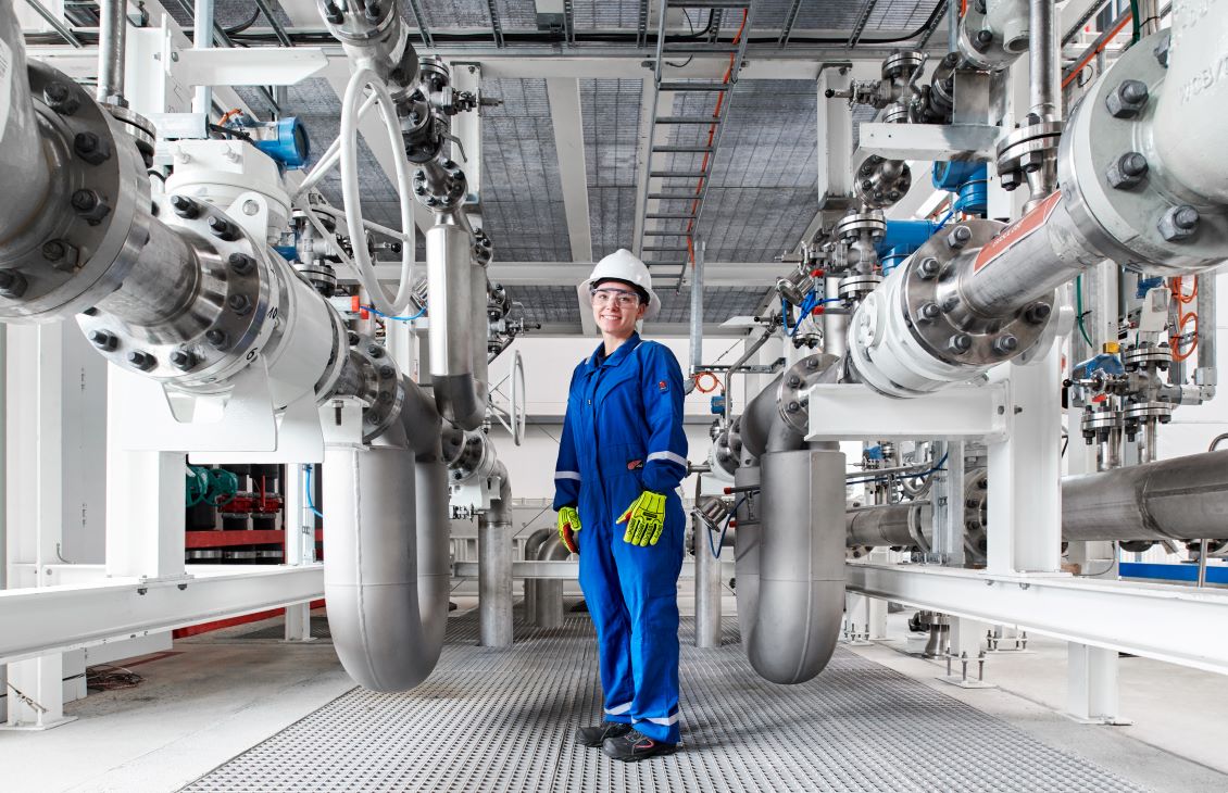 Female SLB Engineer standing in blue coveralls