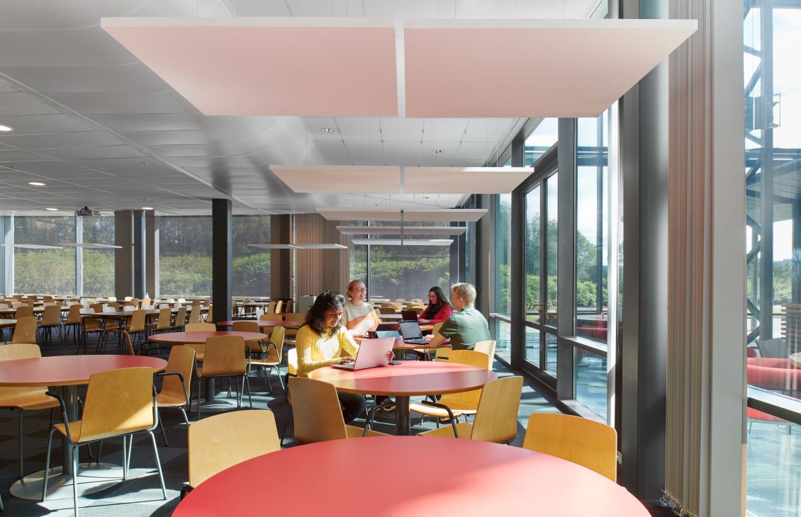 Four SLB employees at red tables with mustard yellow chairs