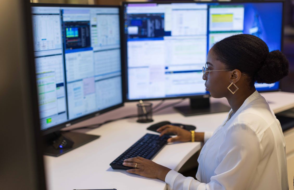 Female SLB employee working on a three screen computer