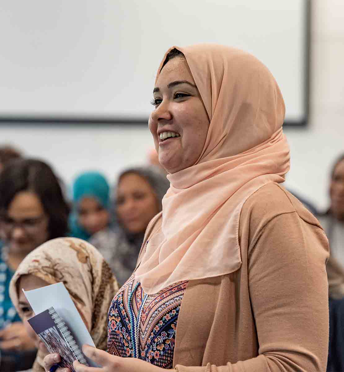 Woman stands in crowd at a conference to ask a question.