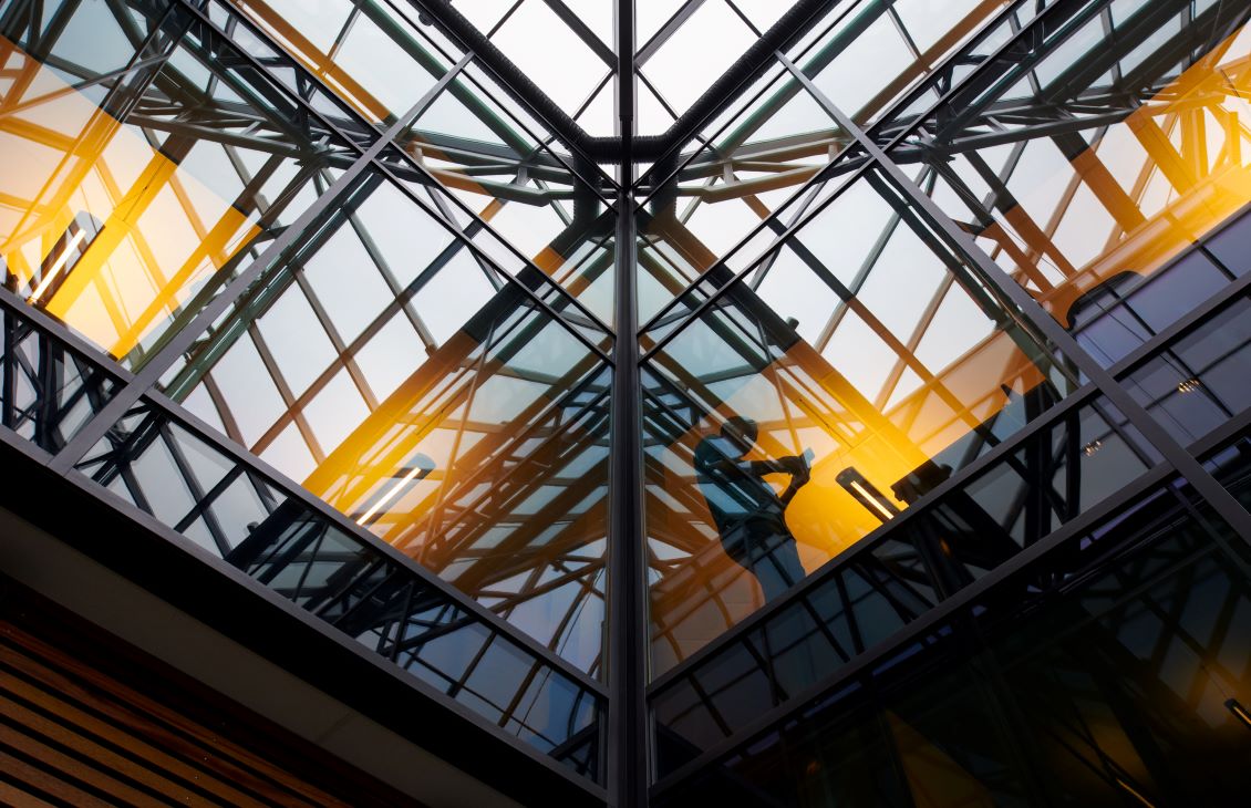 Glass ceiling of the Paris office with a reflection of a man on his phone