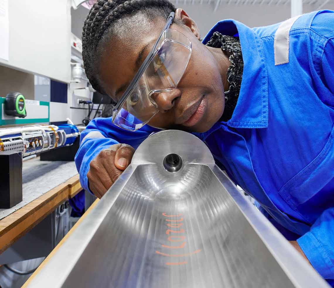 Returnship Program Close up photo of a woman with a machined tool at a manufacturing facility in Sugar Land, TX