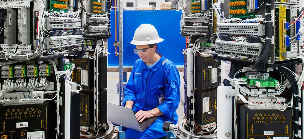 Photo of a woman woking on a laptop at the manufacturing facility in Houston, TX