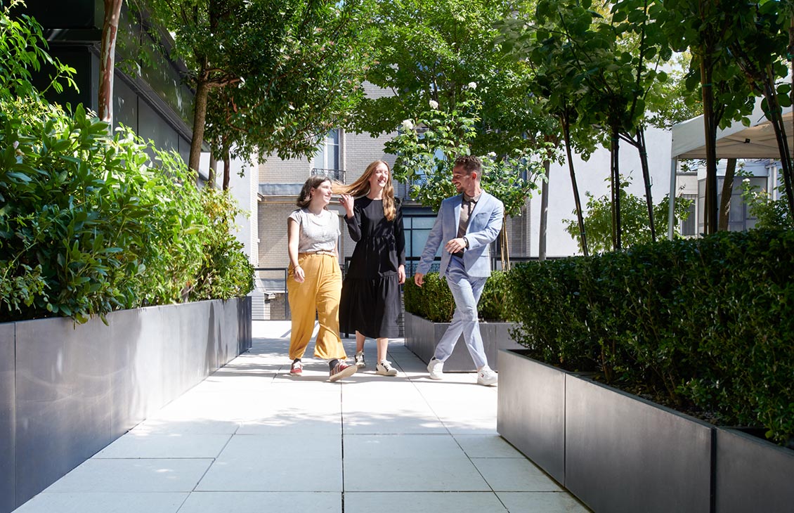 Group of three employees walking on an outside pathway between office buildings